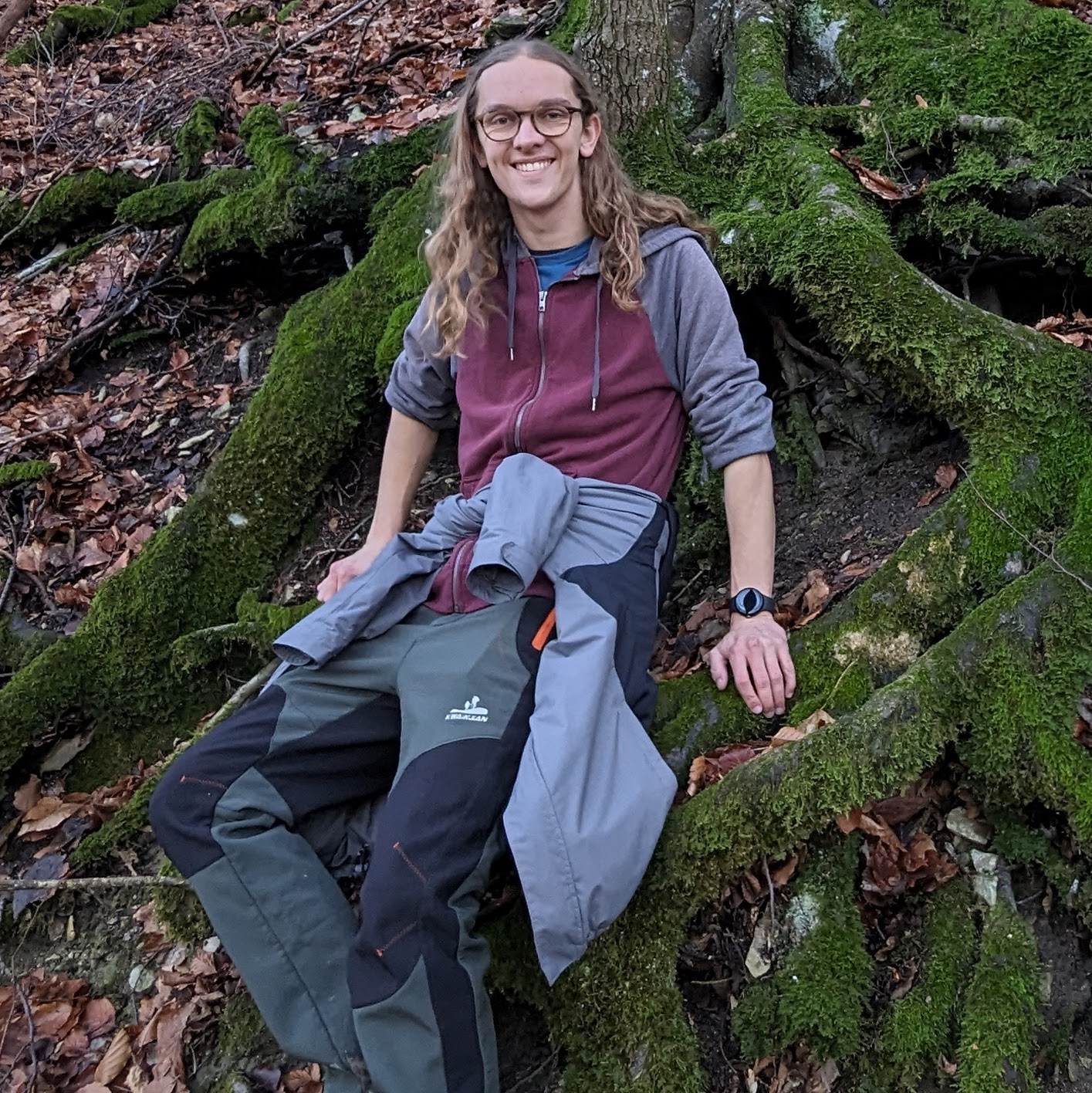 deuce in hiking clothes leaned up against a tree